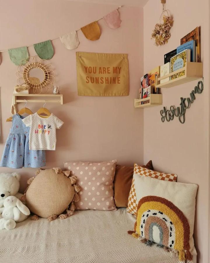 Birch wood Ikea Bekvam shelves in a pastel pink nursery nook by @a.house.on.highlands with cozy cushions and books.