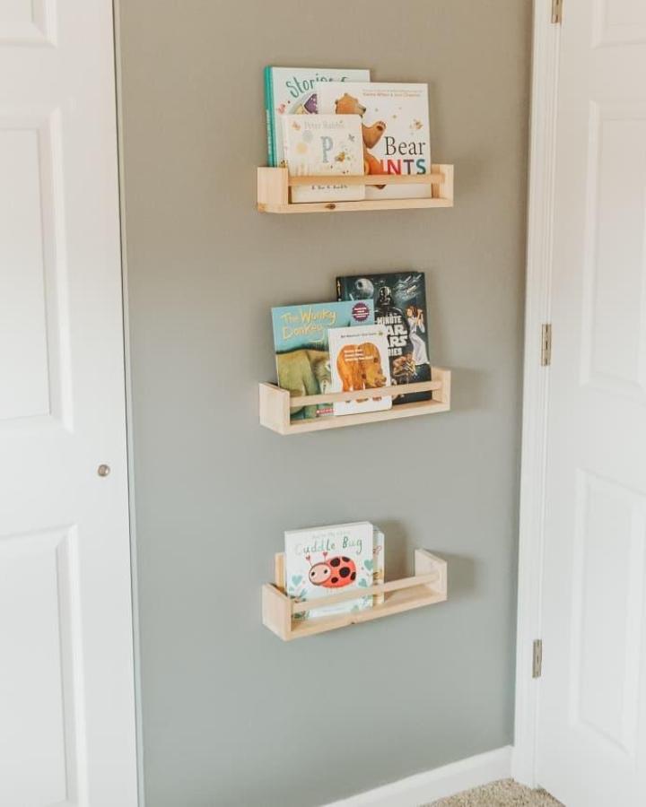 Natural unfinished pine wood wall-mounted book shelves from @grovehousereno. Simple space-saving nursery book organization idea.