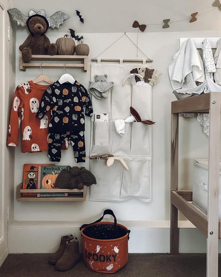 Neutral wooden shelving and seasonal Halloween-inspired nursery storage by @foxgloves_and_wolfe featuring cozy textiles and playful décor.