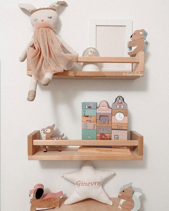 Natural raw wood shelves styled with soft pastel nursery toys by @alessialadya showcasing cozy baby room storage ideas.