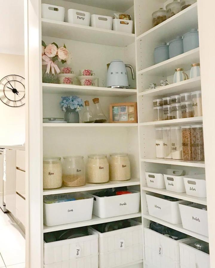 White minimalist pantry storage with labeled bins and pastel accents from @homeorganized99. Organized shelves full of containers and decor.