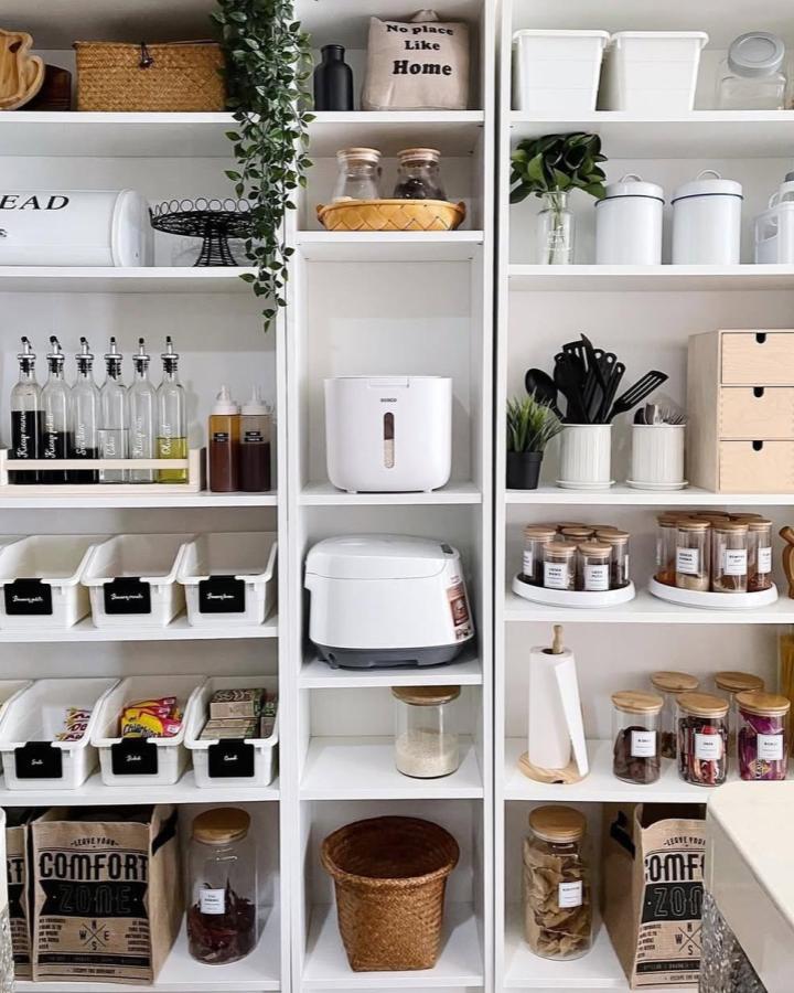 White minimalist pantry shelving with woven baskets and glass jars from @nadddddddia. Organized and stylish kitchen storage solution.