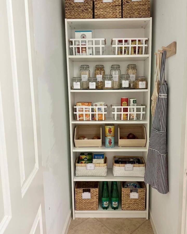 White Billy shelving unit with baskets and jars in pantry by @oliennahome. Organized kitchen storage with woven and wooden bins.