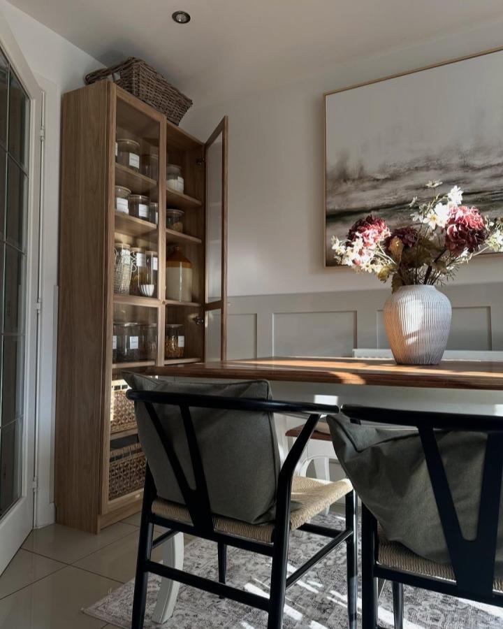 Glass door Ikea Billy pantry ideas by @at_sadieshome featuring warm oak wood and organized jars in a stylish kitchen corner.