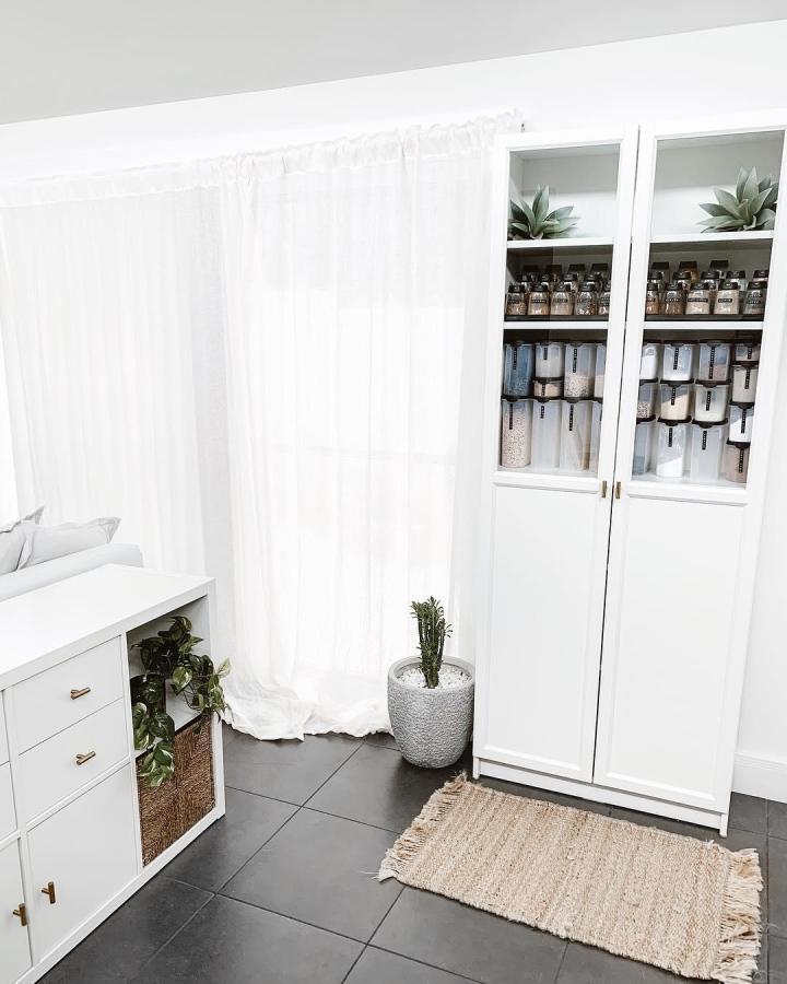 White minimalist Ikea pantry cabinet with half glass doors and labeled containers from @_ashlee_white_ showing organized kitchen storage style.