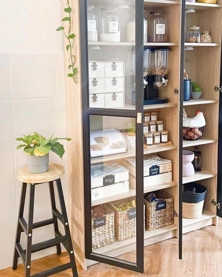 Light wood Ikea Billy pantry with black-framed OXBERG glass doors and organized baskets by @arboldhome showcasing ikea billy pantry ideas. Clean and stylish kitchen storage.