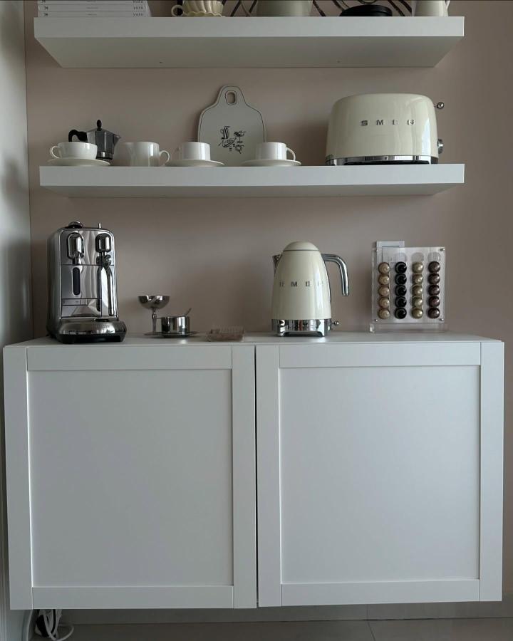 Creamy white floating shelves and cabinet setup from @maison.no.21/. Modern minimalist coffee corner with espresso machine and kettle.