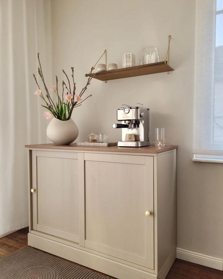 Beige Ikea HAVSTA cabinet coffee station from @achtsam_fuer_schoenes with brass bracket shelf and minimalist decor ikea coffee station ideas.
