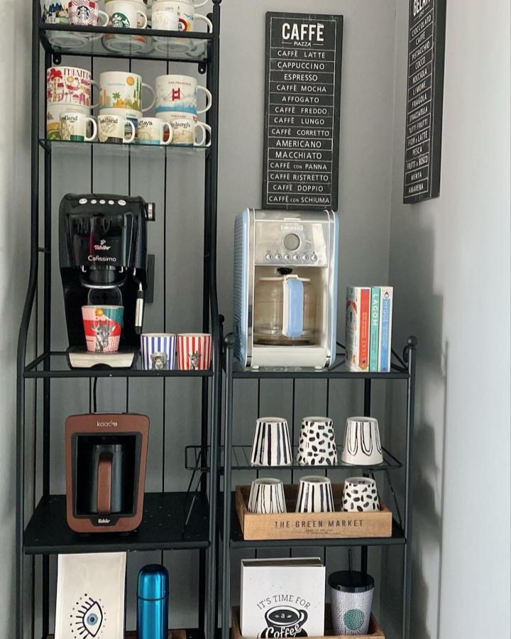 Black metal rack coffee station from @heysevgi featuring colorful mugs and patterned ceramic cups organized neatly on shelves.