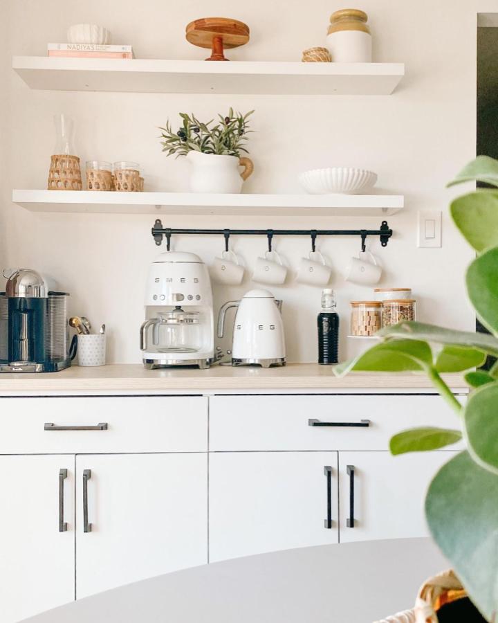 White and light wood coffee station with black rail and simple decor from @honeynjoy. Cozy and organized brewing area.