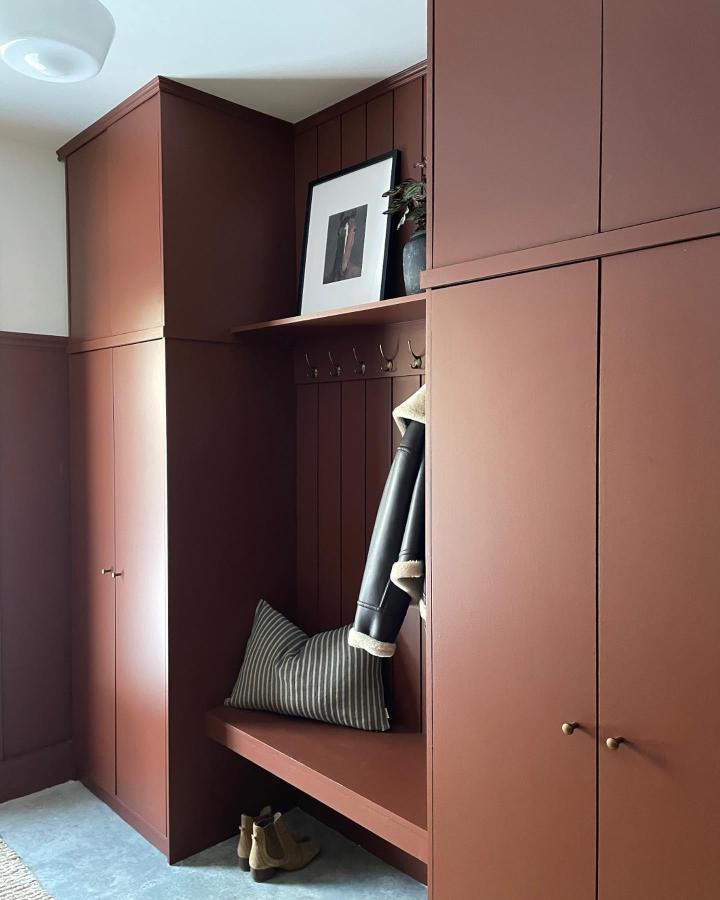 Terracotta wood and brass hallway storage unit by @shoppologie_atelierdesign featuring cozy bench and hooks for entryway organization.