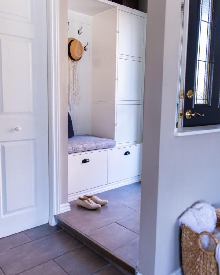 White modern hallway storage and seating area by @suzannekrytondesigns with minimalist locker unit and cushioned bench for entryway organization.