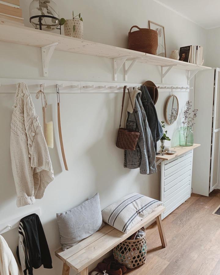 Natural wood and white IKEA entryway setup from @hemmainteriors_ with comfortable bench and clever coat storage hooks. Light and airy.