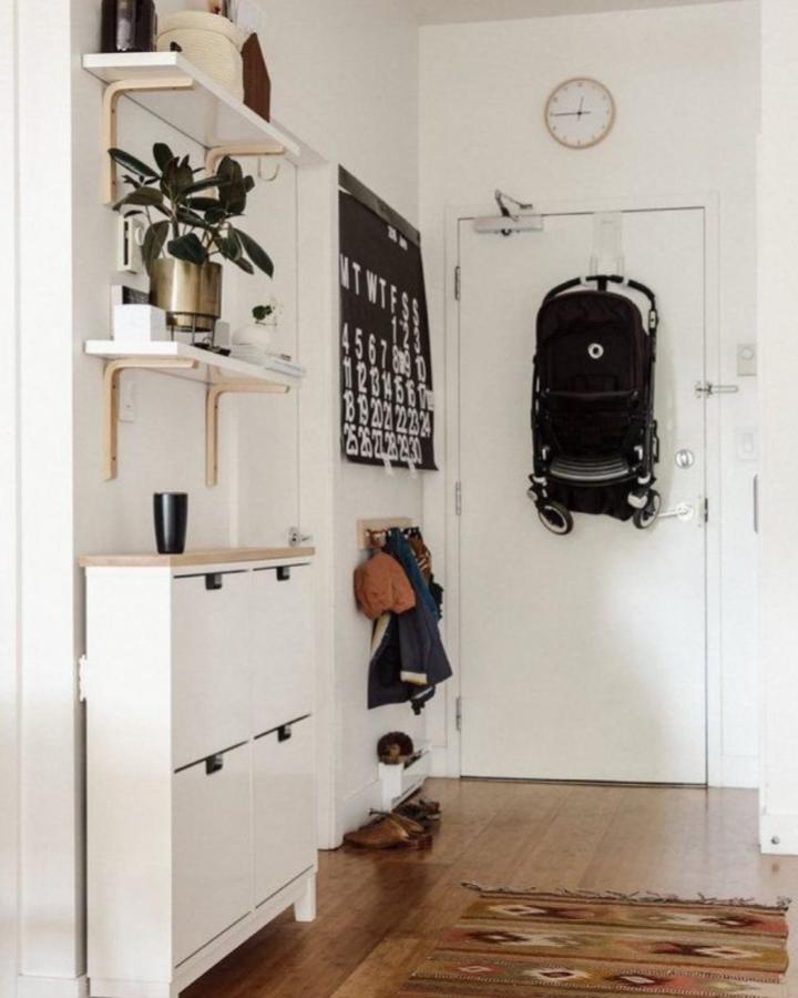 White minimalist shoe cabinet with wood top and wall shelves from @tinydesignliving. Organized and cozy entryway storage and decor.