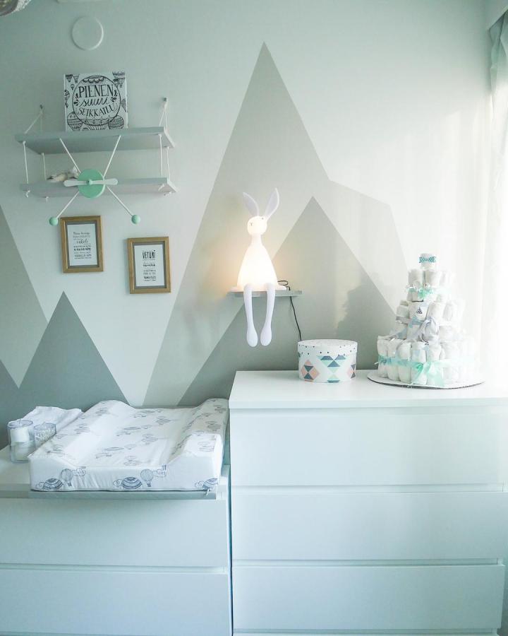White minimalist dresser nursery with geometric mountain wall art and playful baby accents from @meidansuuriseikkailu. Light and airy baby room scene.