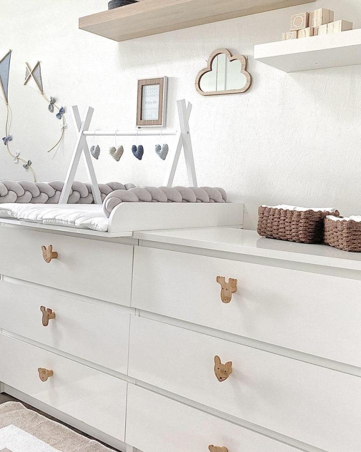 White Malm dresser with wooden animal drawer handles and soft grey braided cushion by @puckdaddy.de nursery setup with natural textures and minimalist decor.