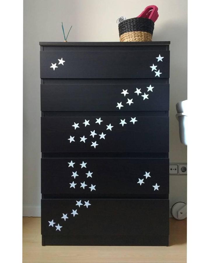 Black Ikea Malm dresser with glowing white star decals from @blanca_river showing a whimsical nursery furniture style.