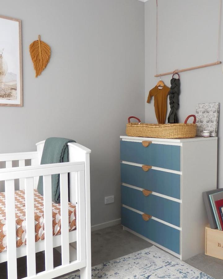 White frame chest with blue drawers and leather handles in a cozy nursery corner by @woolandwillow showing natural texture and calm style.