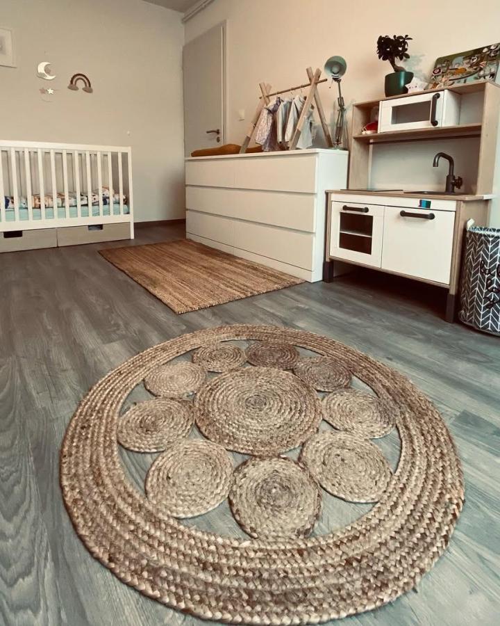 Natural woven round rug with white minimalist dresser and baby items by @medine.ita Scandinavian-inspired cozy playroom design.