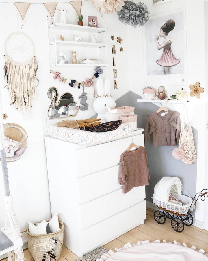 White minimalist dresser nursery corner from @by_bernth with pastel accents and cozy baby clothes details. Clean and charming decor.