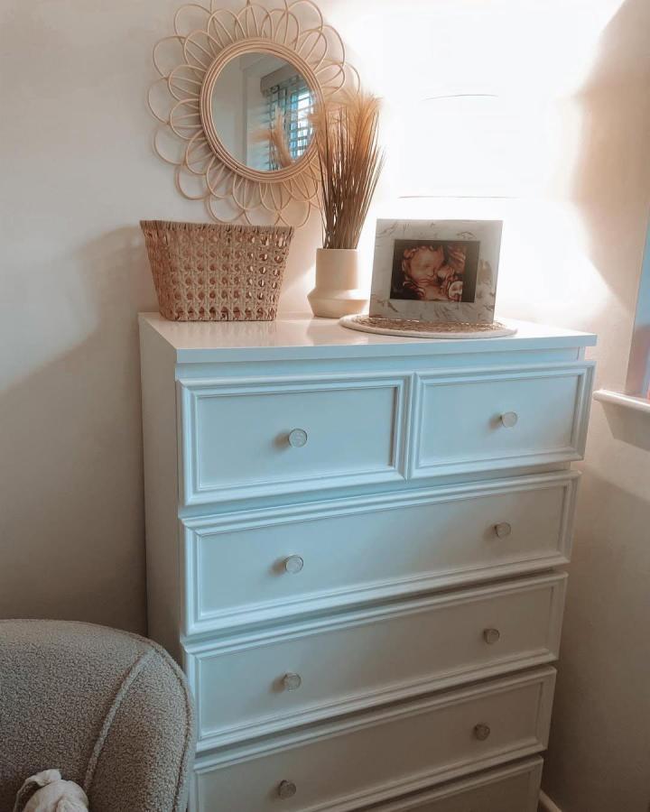 Creamy white Malm dresser with molding detail, woven basket, and soft natural decor from @keepingupwithamylouis. Cozy nursery style.