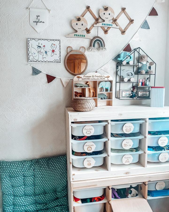 Natural wood Ikea Trofast storage and soft teal cushions from @twinningittogether blend functionality and charm in ikea montessori playroom ideas. Organized labeled boxes and warm accents create an inviting space.