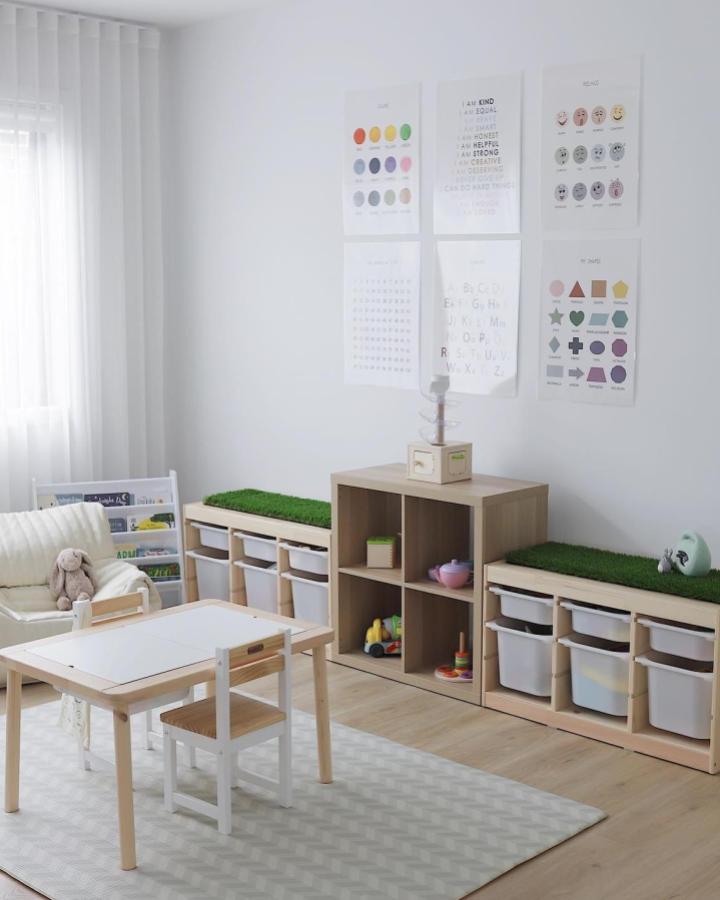 Natural wood Montessori playroom with IKEA Trofast storage and green cushioned benches from @ourhometobe in soft calming colors for children’s learning and play.