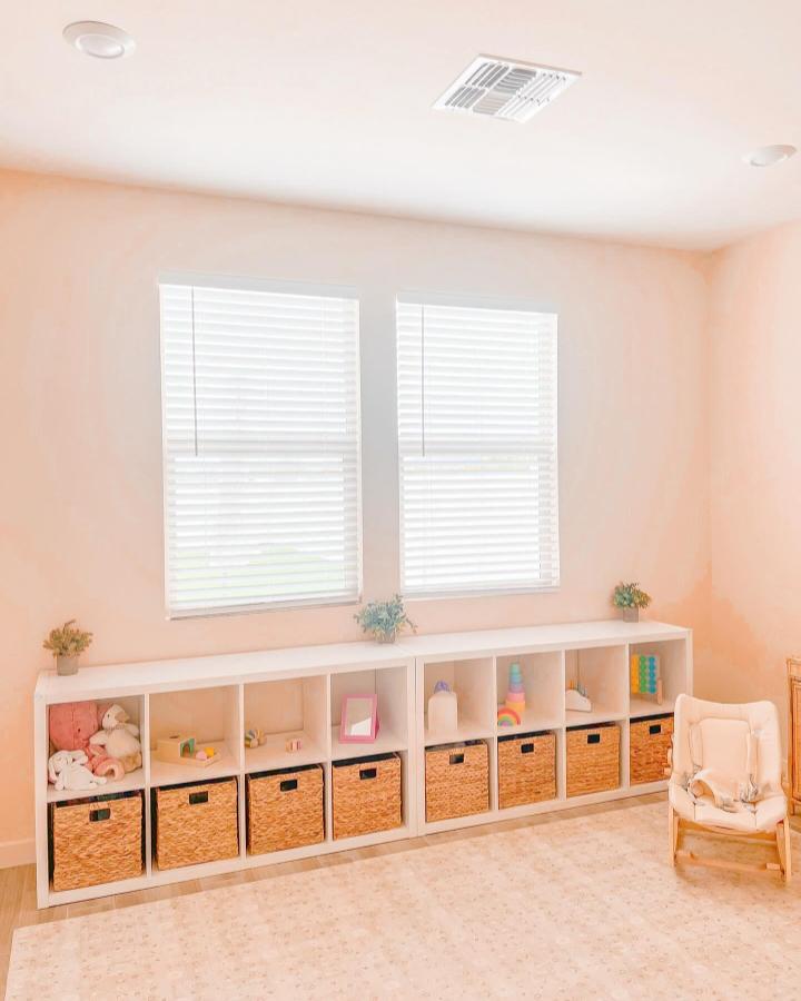 Natural woven baskets and white Kallax shelves in a sunlit Montessori playroom designed by @prettyinpastellie with tidy storage and soft decor.