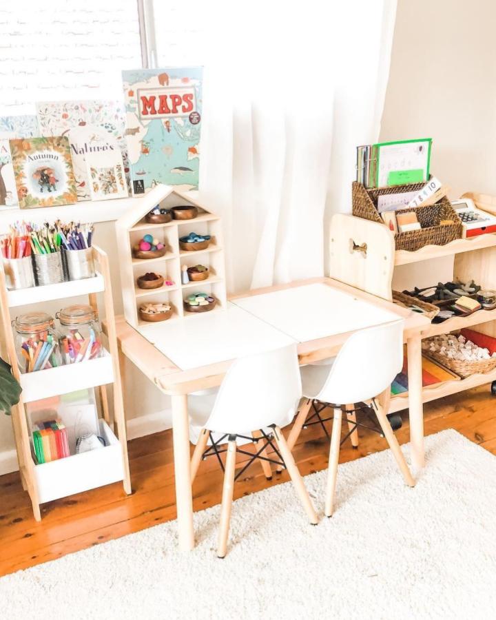 Natural wood and white IKEA FLISAT table and shelves from @where_learning_meets_play bright kids creative space with art supplies and books.