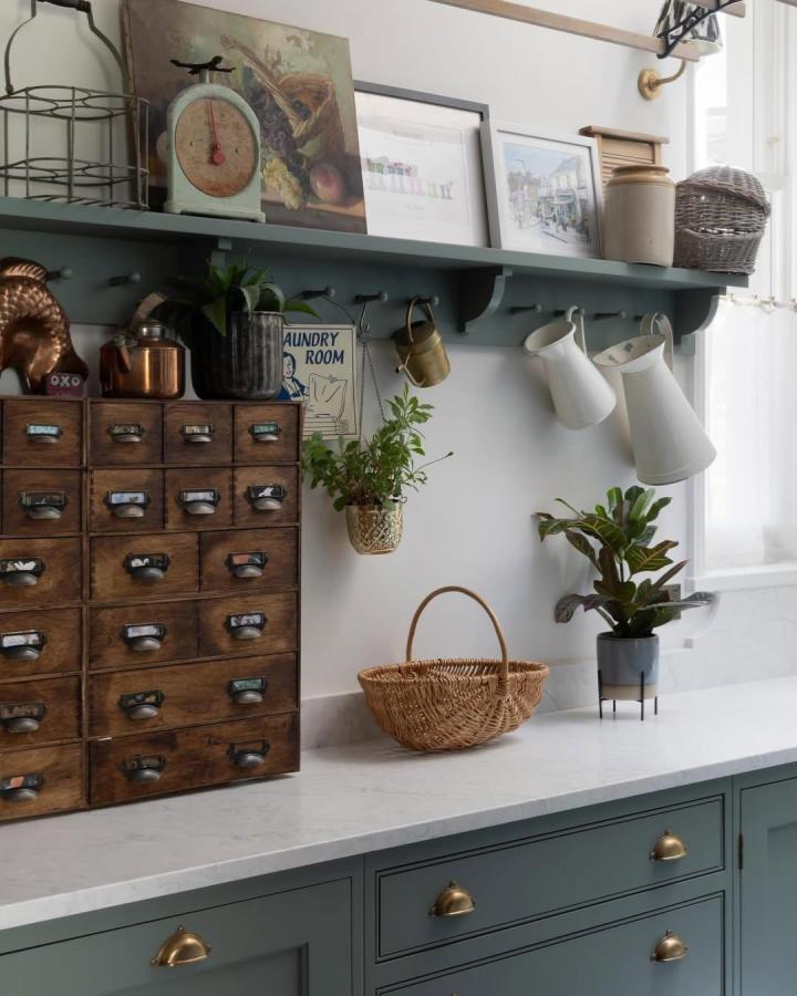 Vintage-style wooden apothecary drawers and sage green shelf with hanging pitchers and plants inspired by @upstyleyourhome. Charming IKEA furniture redo.