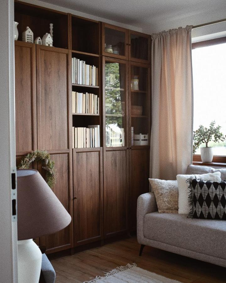 Walnut built-in storage with glass doors and closed cabinets in cozy living room by @dom.malinowy. Stylish and budget-friendly furniture upgrade.