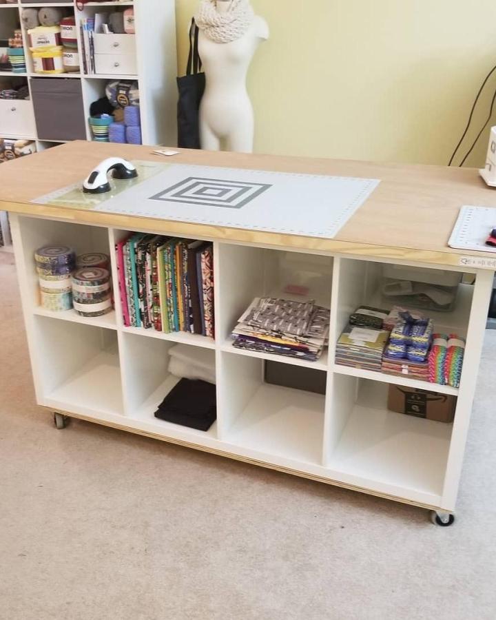 White Ikea Kallax storage unit with wooden tabletop and caster wheels by @happeeknits Craft workspace with fabric organization and movable base.