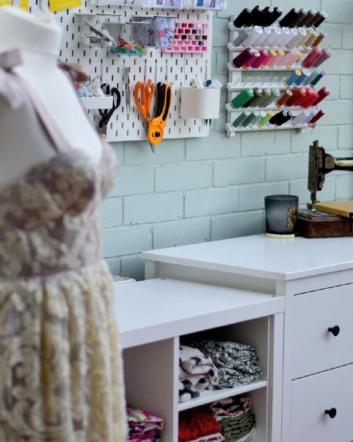White minimalist sewing table with Koppang drawers and Skadis pegboard from @ginaseams neatly organizing colorful thread and tools in a craft room.