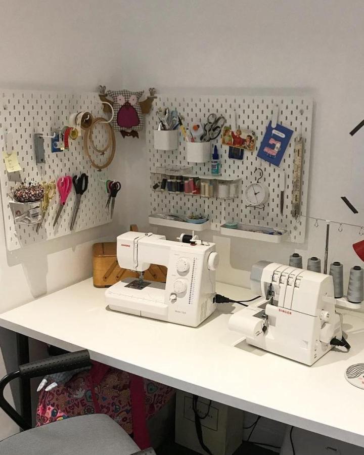 White Ikea Skådis pegboards with sewing tools and machines from @renovation.x showing neat ikea sewing table ideas. Compact and organized craft area.