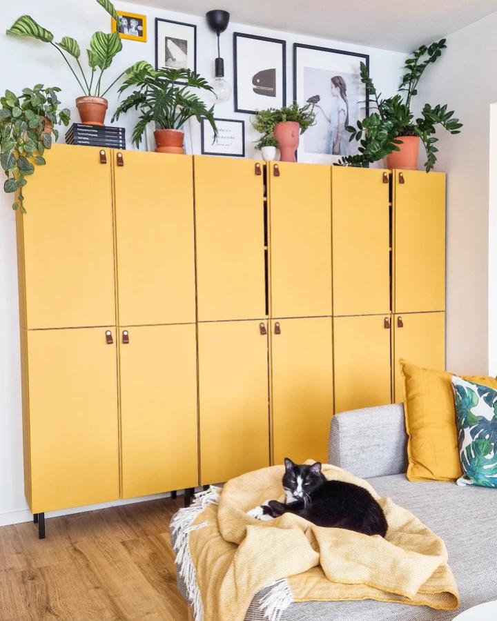 Bright yellow Ikea Ivar cabinet with leather pulls and plants on top from @yellow.jungle in a compact living area providing stylish storage solutions