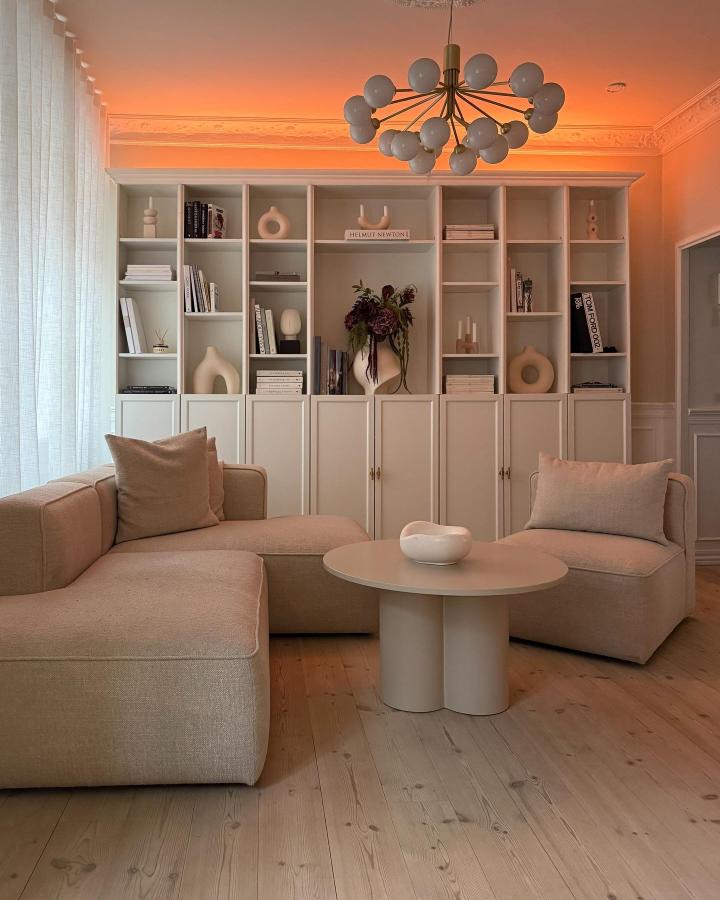 Beige Billy bookcase with custom cabinet doors in cozy small living room by @rasmus.malling with soft lighting and minimalist decor