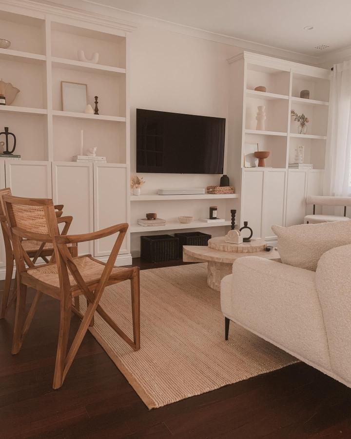 White built-in style Billy bookshelf with natural wood chair and neutral textiles from @carmenchia. Cozy, small living room storage and style solution.