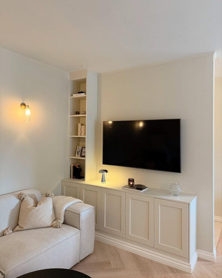 Beige built-in storage unit with open shelves and panelled doors by @flippmedhe for compact living room organization and style.