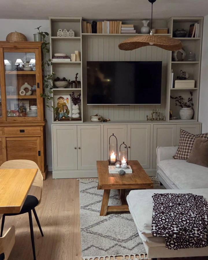 Muted green painted built-in using IKEA havst chest and billy shelves from @paula_homeandliving in a small cozy living space with warm wood accents and decor