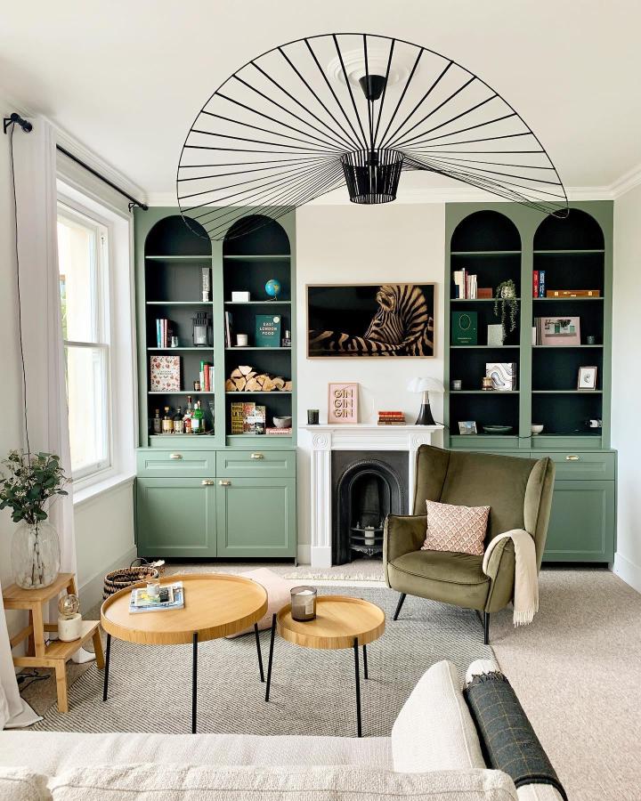 Moss green built-in shelving unit with brass handles and arched tops by @romy_ring Stylish cozy living room storage solution.