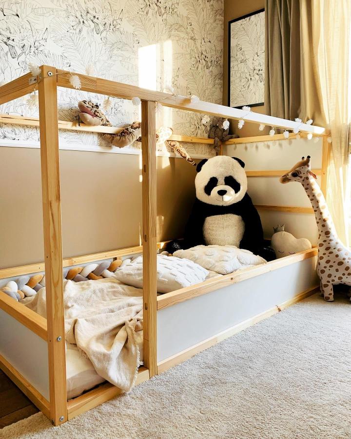 Warm natural wood KURA bed from @dominika.byczek. Fairy lights, plush toys, and cozy Scandinavian bedding create a snug nook.