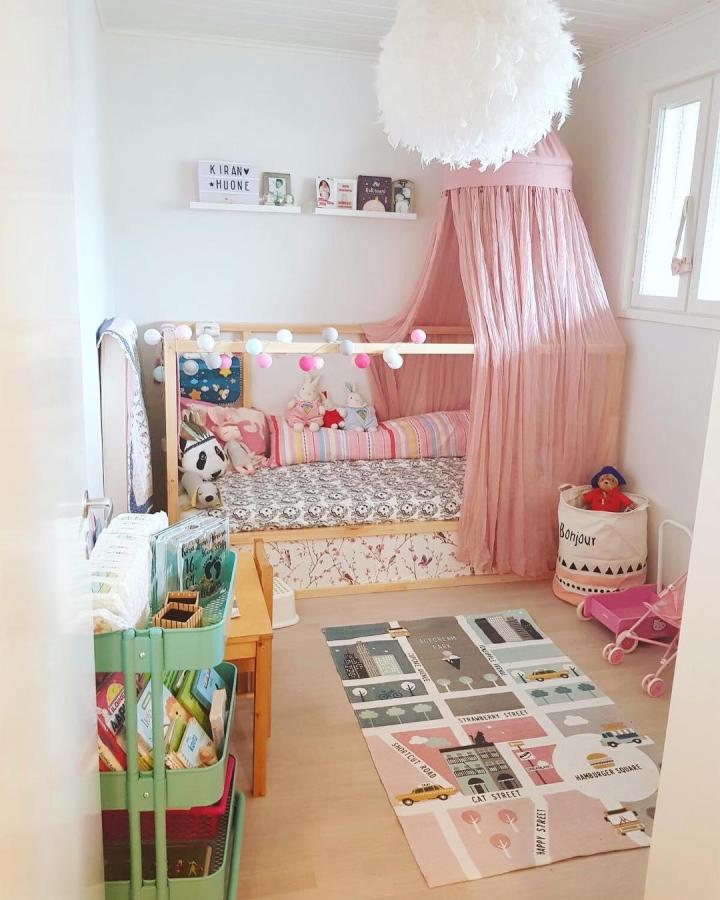 Pink canopy KURA bed from @mirapajari. Pom-pom lights create a cheerful children’s retreat.