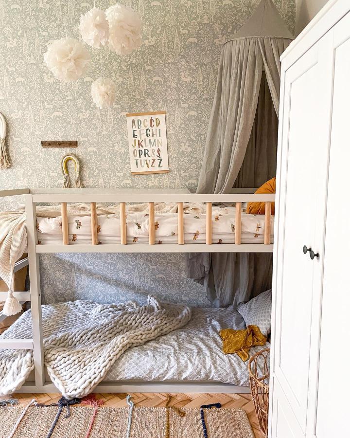 Grey canopy KURA bed from @urska_oman. Chunky knit blanket, floral bedding, and cozy nursery styling.