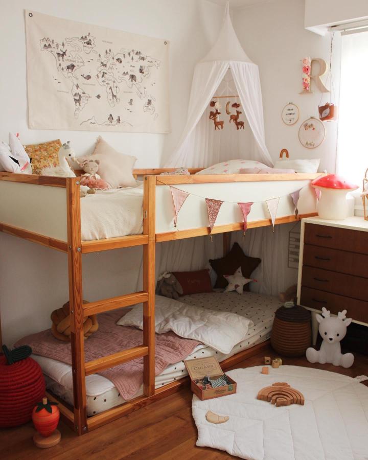 Natural wood children's bedroom with KURA bunk bed from @manon_and_cie. White hanging canopy and blush bunting.