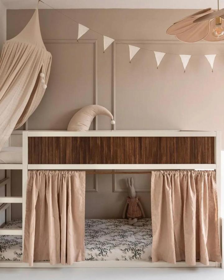 Warm oak slatted KURA bed from @kidsinteriors_com. Under-bed curtains create a cozy play nook.