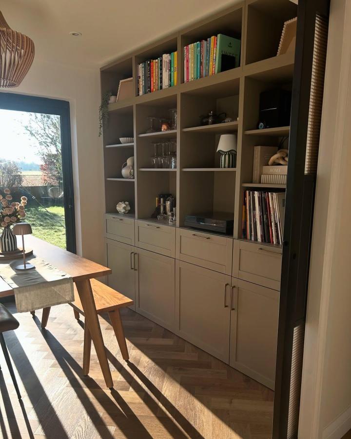 Taupe built-in dining storage from @the_eighteenth_house. Open shelves, books, cupboards, and drawers create a refined fitted wall.