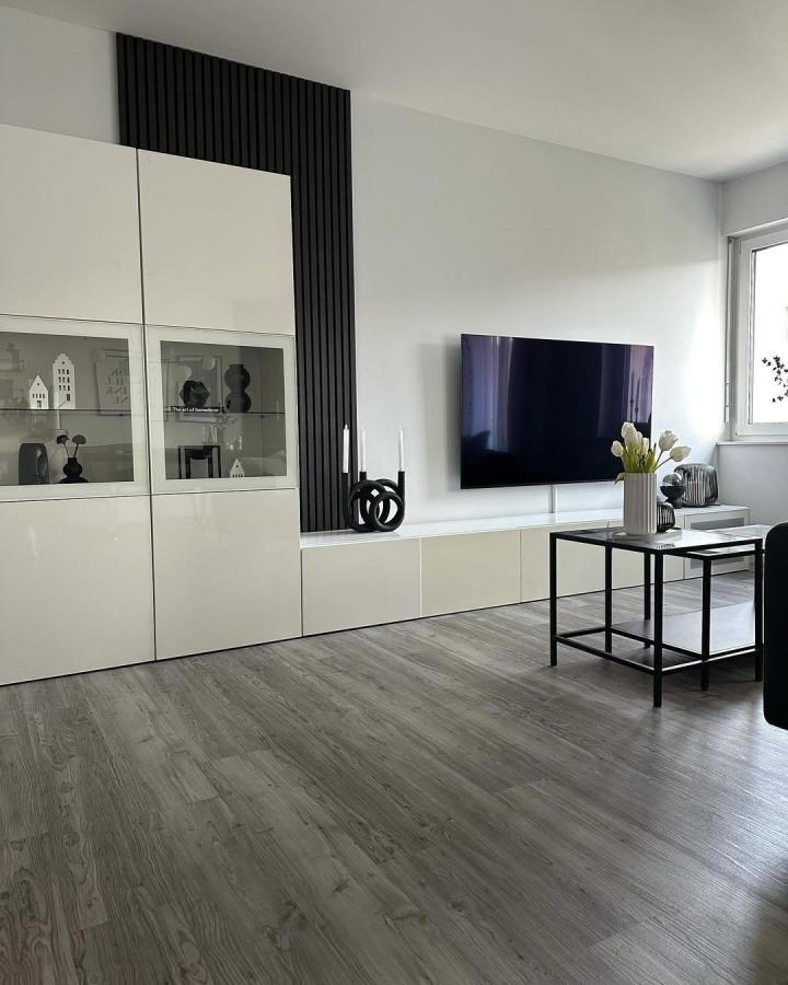 White and black living room media wall from @allabout.homedecor. Sleek Besta cabinetry with vertical slat detailing.