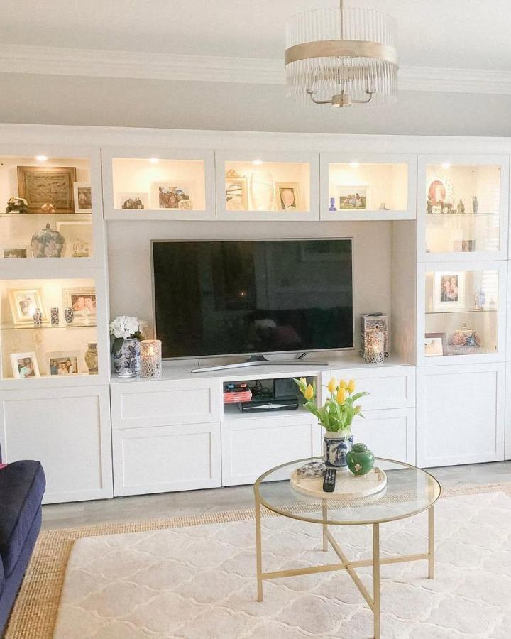 White framed living room media wall from @southernoutlook. Besta cabinets flank a television with lit display shelves.