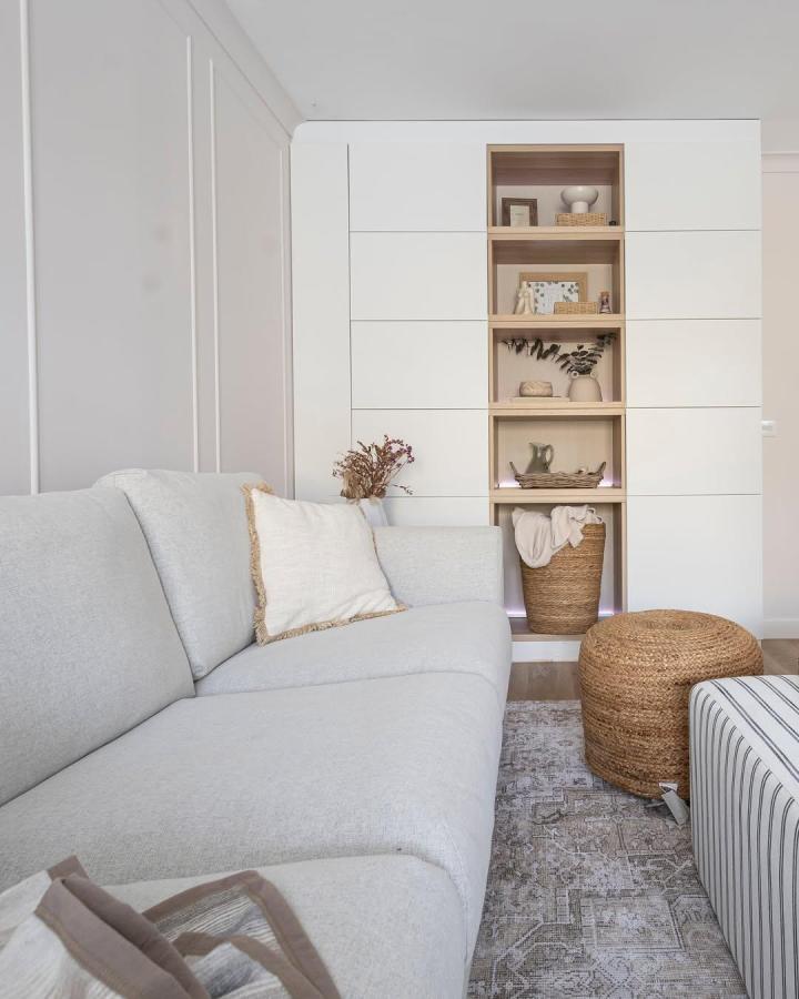 White oak-accented living room storage wall from @sirokova.design.and.art. Central niches display ceramics and baskets.