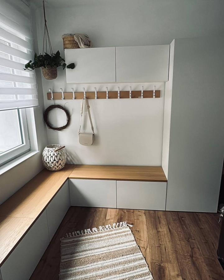 White oak-accented entryway storage from @tatjanahummels. Wall-mounted cabinets, hooks, and corner bench create a custom nook.
